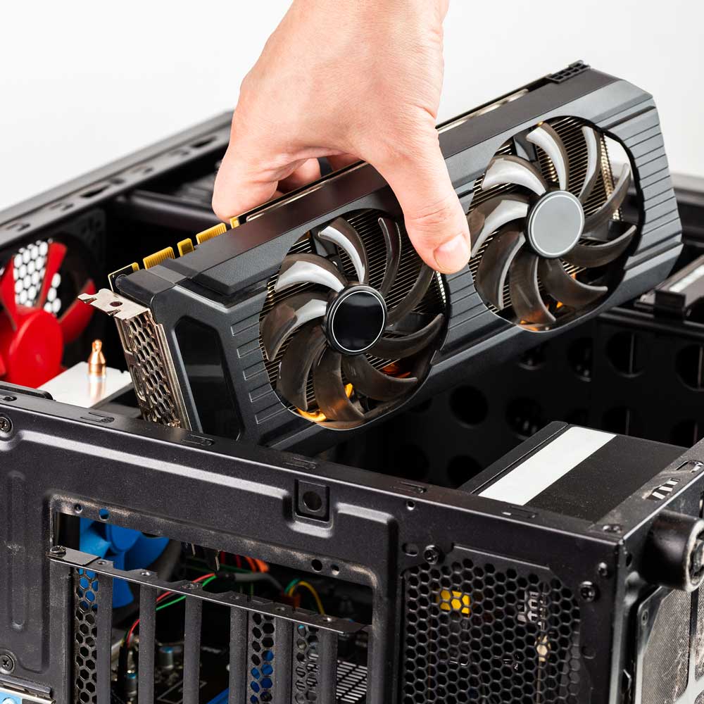 Hand installing a graphics card into a computer case with visible cooling fans.