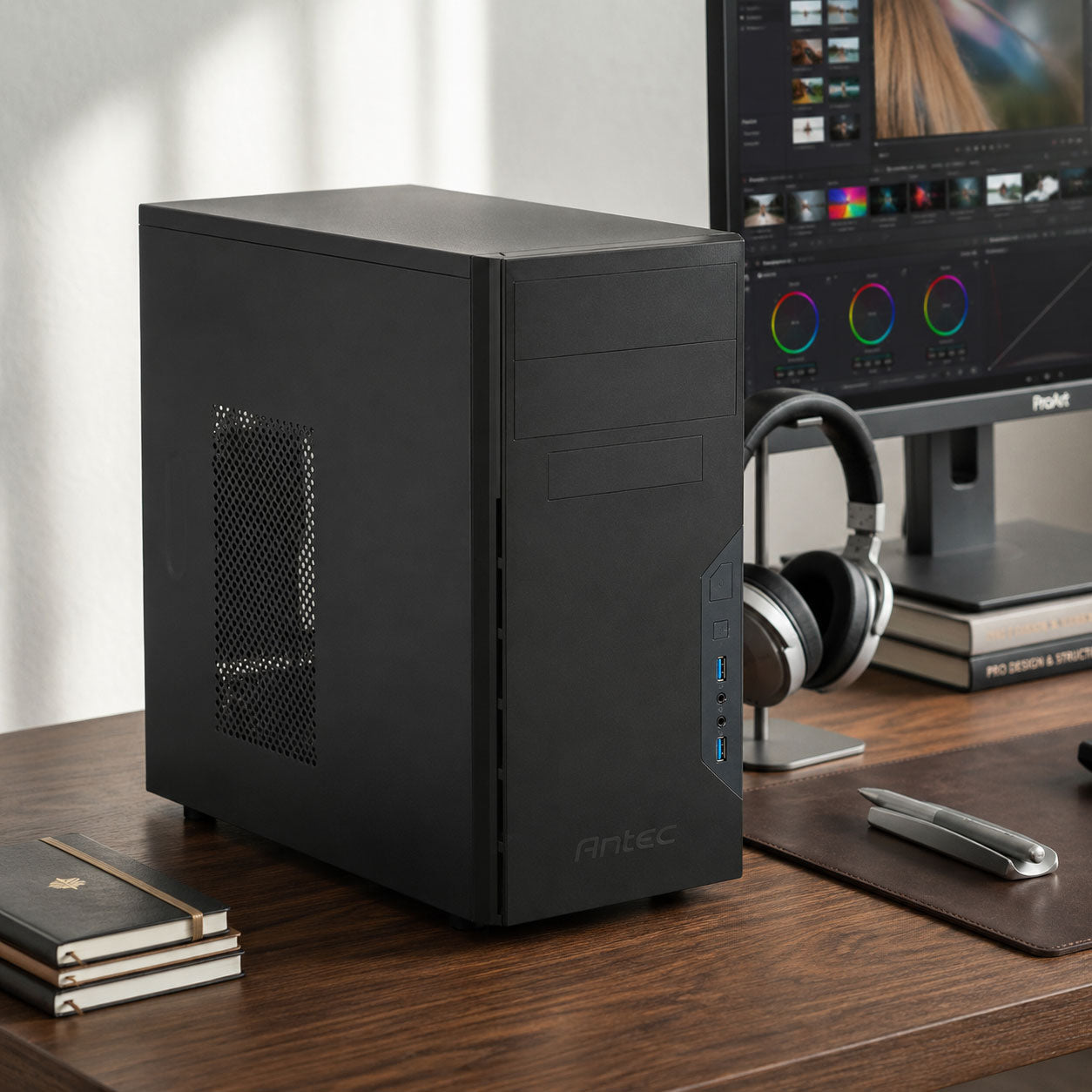 A black Local AI Workstation desktop computer tower sits on a wooden desk in a home office setup, with a computer monitor, headphones, and stacked notebooks nearby.
